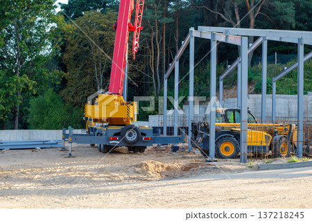 Orange mobile crane and telescopic handler. Construction equipment at the construction site of a building under construction Orange mobile crane and telescopic handler. Construction equipment at the construction site of a building under construction 137218245