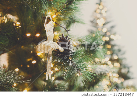 Christmas tree holiday background. Xmas magic and beauty. Fluffy pine tree branches with pinecones with snow and decorated with elegant toy ballerina and garland, closeup, copy space, selective focus Christmas tree holiday background. Xmas magic and beauty. Fluffy pine tree branches with pinecones with snow and decorated with elegant toy ballerina and garland, closeup, copy space, selective focus 137218447