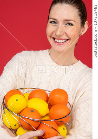 Smiling and happy young woman with fruits in hands Smiling and happy young woman with fruits in hands 137218465