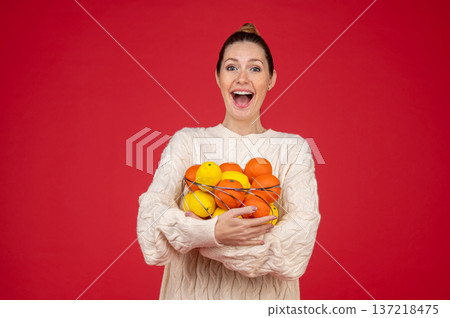 Smiling and happy young woman with fruits in hands Smiling and happy young woman with fruits in hands 137218475