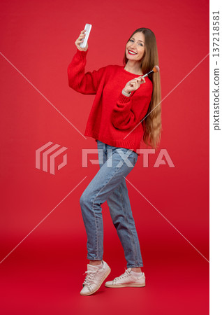 Young pretty woman in red sweater with a facial brush in hands Young pretty woman in red sweater with a facial brush in hands 137218581