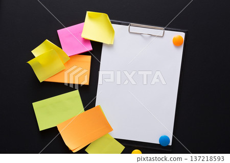 Brightly colored sticky notes surround a blank clipboard, creating an inviting workspace that encourages creativity and idea generation. Perfect for planning or collaborative tasks. 137218593