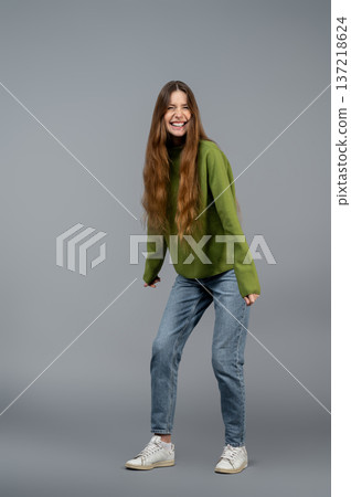 Long-haired young woman on a grey background posing and feeling good Long-haired young woman on a grey background posing and feeling good 137218624