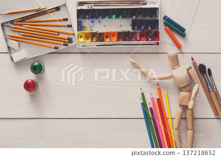 Painting visual art background. Paints and wooden painter man with brushes on white desk, top view, flat lay, objects Painting visual art background. Paints and wooden painter man with brushes on white desk, top view, flat lay, objects 137218652