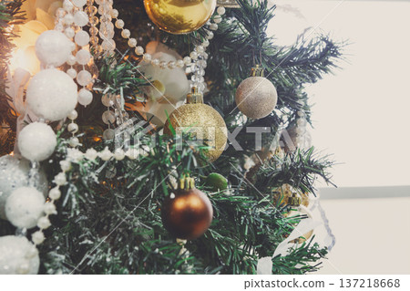 Winter holidays atmosphere background. Closeup of beautifully decorated fir tree with modern shiny baubles, beards and garland. Christmas and new year magic at home with copy space on window Winter holidays atmosphere background. Closeup of beautifully decorated fir tree with modern shiny baubles, beards and garland. Christmas and new year magic at home with copy space on window 137218668
