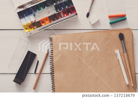 Artist working space background. Watercolor paints and blank craft paper on white wooden desk, top view, flat lay, copy space 137218679