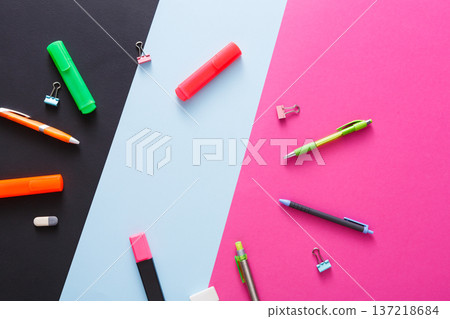 A vibrant collection of stationery items is displayed against a black and colorful backdrop. Writing instruments, paper clips, and a marker are strategically placed to inspire creativity. A vibrant collection of stationery items is displayed against a black and colorful backdrop. Writing instruments, paper clips, and a marker are strategically placed to inspire creativity. 137218684