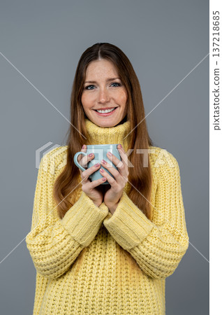 Smiling cute caucasian young woman with a coffee cup in hands Smiling cute caucasian young woman with a coffee cup in hands 137218685