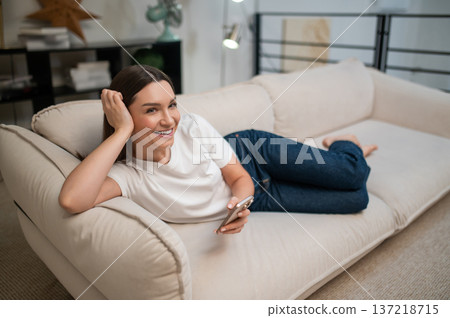 Cute young woman with a phone in hands looking dreamy and excited 137218715
