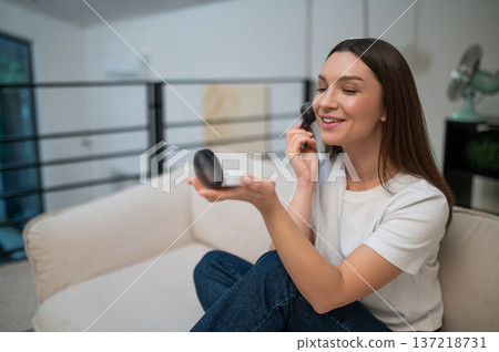 Young woman sitting on the sofa and doing make up Young woman sitting on the sofa and doing make up 137218731