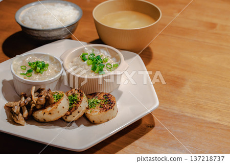 木桌上的日式套餐:米飯、味噌湯、一小碗蒸捲心菜和烤白蘿蔔。 木桌上的日式套餐:米飯、味噌湯、一小碗蒸捲心菜和烤白蘿蔔。 137218737