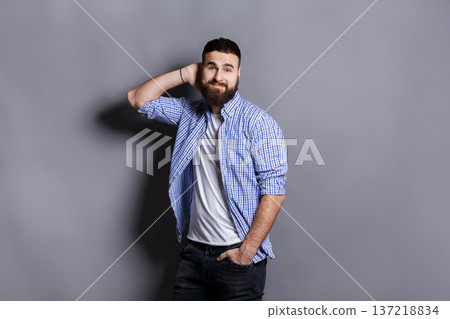 Handsome bearded man touching his hair. Young confident guy in relaxed pose, gray studio background. Flirt, seduction concept 137218834