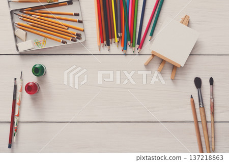 Artist workspace. Drawing tools, stationary supplies, workplace of artist. Watercolor paints and blank paper on white wooden desk, top view, flat lay, copy space 137218863