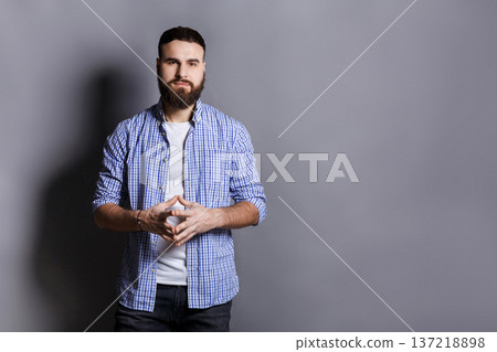 Bearded man with public speaker gesture. Fingers connected at fingertips, pose which imposes power and patience, gray studio background, copy space Bearded man with public speaker gesture. Fingers connected at fingertips, pose which imposes power and patience, gray studio background, copy space 137218898