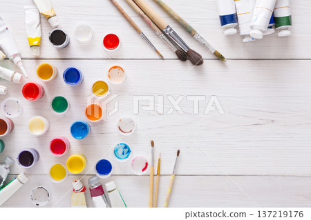 Artist workplace. Set of color gouache jars and acrylic paints on white wooden desk background, top view, copy space Artist workplace. Set of color gouache jars and acrylic paints on white wooden desk background, top view, copy space 137219176