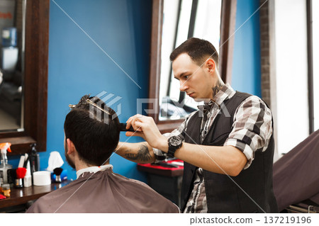 Barbers working in barbershop with hair of clients. Making modern hairstyle in male hair salon 137219196