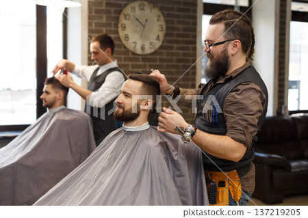 Barber make haircut with scissors at barbershop. Stylish hairdresser in male hair salon Barber make haircut with scissors at barbershop. Stylish hairdresser in male hair salon 137219205