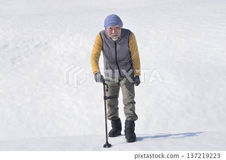 一位老人在雪地裡拄著拐杖做復健訓練。 一位老人在雪地裡拄著拐杖做復健訓練。 137219223