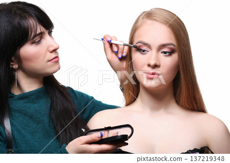 Make-up artist applying makeup for beauty model with eyeshadow palette, isolated on white background 137219348