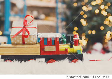 Wooden toy train with christmas gift on snowy decorated background. Selective focus, copy space 137219414