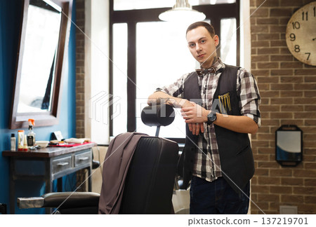 Stylish barber wait for client. Young professional haitstylist in male barbershop Stylish barber wait for client. Young professional haitstylist in male barbershop 137219701