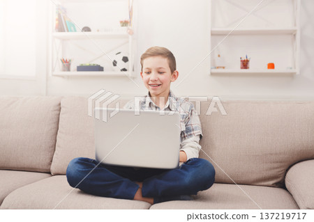 Boy has fun with computer at home. Children and internet, modern technology concept Boy has fun with computer at home. Children and internet, modern technology concept 137219717