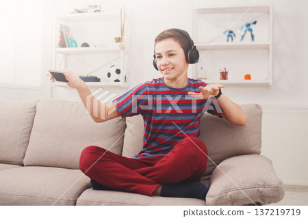 Joyful teenage boy enjoying music in headphones at home. Relax time Joyful teenage boy enjoying music in headphones at home. Relax time 137219719