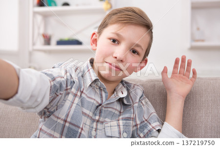 Happy child making selfie for social networks. Boy at home on sofa in living room Happy child making selfie for social networks. Boy at home on sofa in living room 137219750