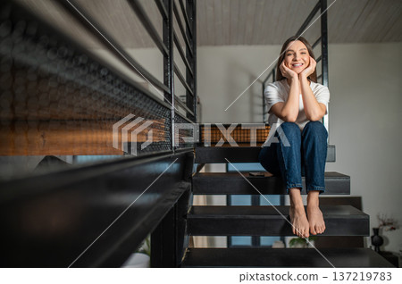 Young woman sitting on the stair in her apartment Young woman sitting on the stair in her apartment 137219783