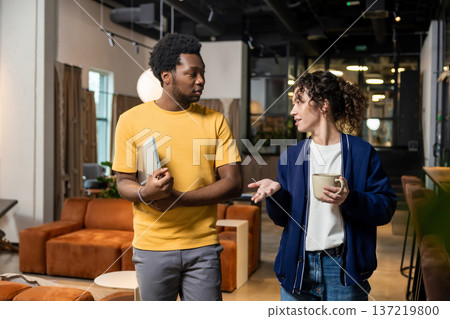Woman holding coffee and man with notebook conversing Woman holding coffee and man with notebook conversing 137219800