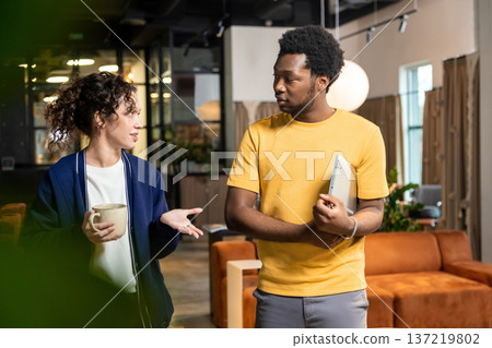 Woman with coffee cup and man holding notebook communicating posing in coworking office Woman with coffee cup and man holding notebook communicating posing in coworking office 137219802