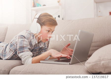 Child blogging in internet, concentrated boy with laptop at home 137219817