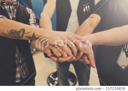 Men friendship. United hands of young team with tattoo. Unity and teamwork concept Men friendship. United hands of young team with tattoo. Unity and teamwork concept 137219839