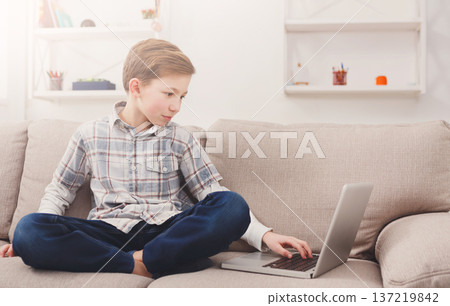 Small boy using laptop on couch at home. Child and internet Small boy using laptop on couch at home. Child and internet 137219842