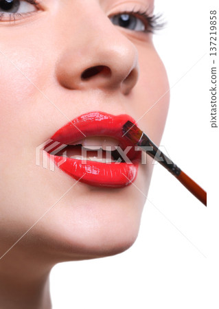 Lips makeup closeup. Apply lipstick with brush. Close-up of female model face with fashion glossy red make-up, beauty concept isolated Lips makeup closeup. Apply lipstick with brush. Close-up of female model face with fashion glossy red make-up, beauty concept isolated 137219858