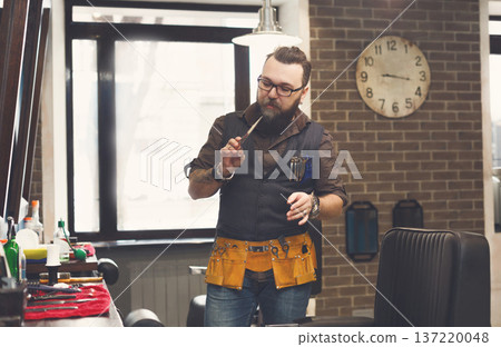 Experienced bearded barber at workplace in barbershop. Professional stylish hairdresser waiting for client at hair salon Experienced bearded barber at workplace in barbershop. Professional stylish hairdresser waiting for client at hair salon 137220048