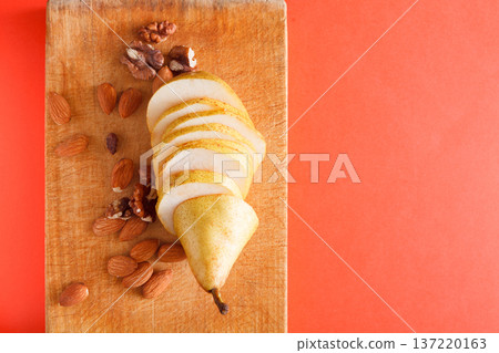 Healthy food, sliced pear on wooden board with almonds and walnuts on bright background, diet and vegetarian concept, top view, copy space Healthy food, sliced pear on wooden board with almonds and walnuts on bright background, diet and vegetarian concept, top view, copy space 137220163