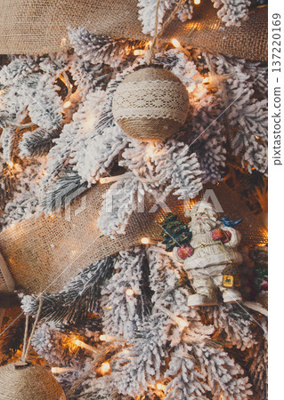 Winter holidays atmosphere background. Closeup of beautifully decorated fir tree with modern shiny baubles, beards, garland and small santa . Christmas and new year magic at home, copy space Winter holidays atmosphere background. Closeup of beautifully decorated fir tree with modern shiny baubles, beards, garland and small santa . Christmas and new year magic at home, copy space 137220169