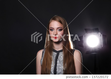 Beautiful woman model on black background with copy space, fashion shooting. Girl with makeup, perfect skin and hair posing to camera at studio 137220172
