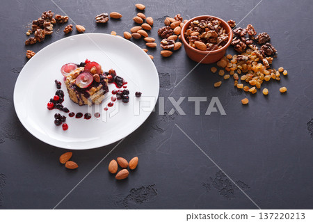 Healthy eating, dieting and detox concept - wholegrain fresh oatmeal porridge with fruits, berries and nuts on dark background. 137220213