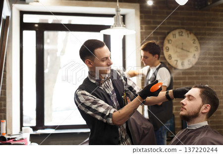 Barbers in barbershop with clients. Making modern hairstyle in male hair salon 137220244