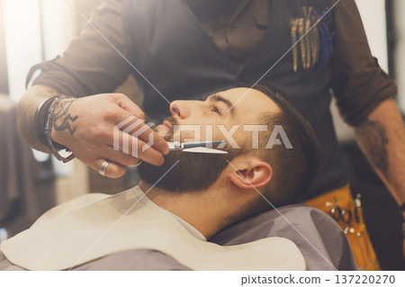 Barber make beard haircut with scissors in barbershop, closeup of client's head. Hairstyle in male hair salon Barber make beard haircut with scissors in barbershop, closeup of client's head. Hairstyle in male hair salon 137220270