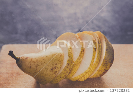 Sliced pear on wooden board background, selective focus, copy space, healthy food, diet and vegetarian concept Sliced pear on wooden board background, selective focus, copy space, healthy food, diet and vegetarian concept 137220281