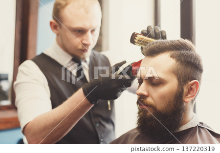 Man getting haircut by hairstylist at barbershop. Stylish barber and client Man getting haircut by hairstylist at barbershop. Stylish barber and client 137220319