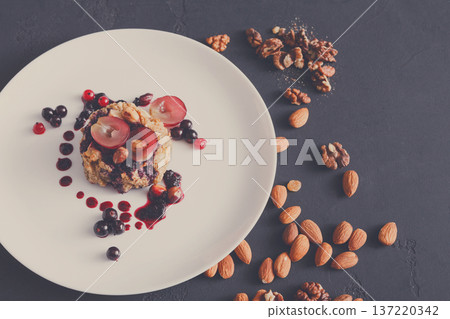 Healthy eating, dieting and detox concept - wholegrain fresh oatmeal porridge with fruits, berries and nuts on dark background. 137220342