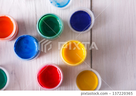 Artist workplace. Set of color gouache jars and acrylic paints on white wooden desk background, top view, copy space Artist workplace. Set of color gouache jars and acrylic paints on white wooden desk background, top view, copy space 137220365