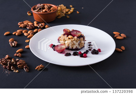 Healthy eating, dieting and detox concept - wholegrain fresh oatmeal porridge with fruits, berries and nuts on dark background. Healthy eating, dieting and detox concept - wholegrain fresh oatmeal porridge with fruits, berries and nuts on dark background. 137220398