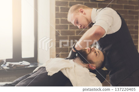 Barber styling beard to client at barbershop. Stylish hairdresser in male hair salon 137220405