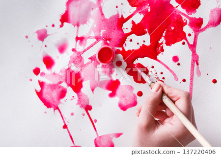 Artist creating watercolor painting. Brush and paint jar in female hands. Bright red drops on paper texture. Modern art backgroung with copy space 137220406