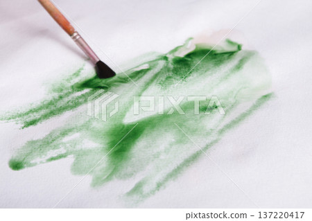 Artist creating watercolor painting. Expressive brush strokes of green aquarelle on paper texture. Modern art backgroung with copy space 137220417